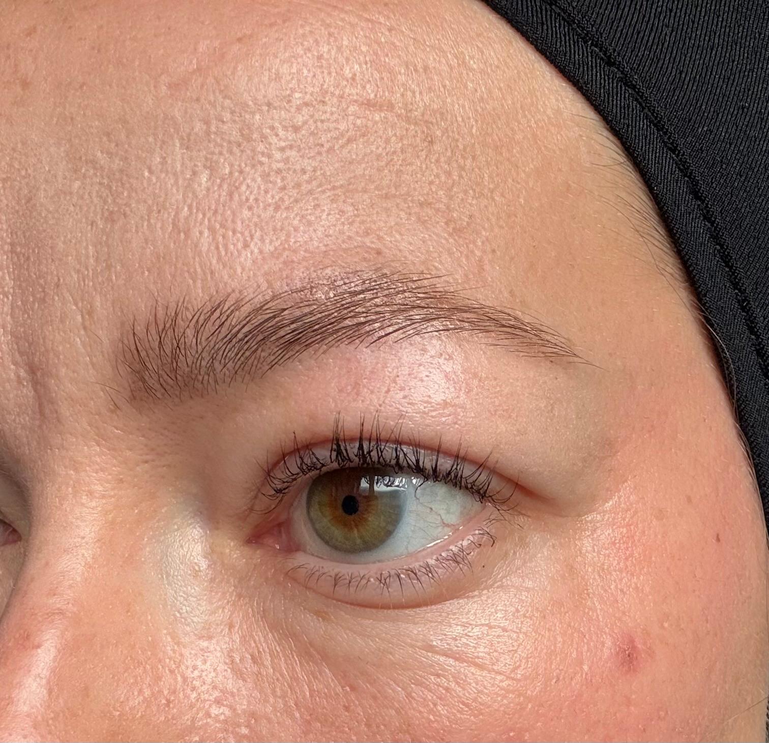 Oog met gelifte wimpers en verzorgde wenkbrauw na de behandeling