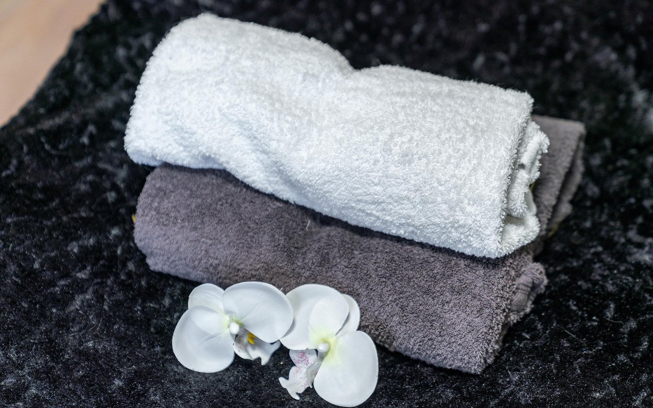 Opgerolde handdoeken met een witte orchidee op zwarte stof